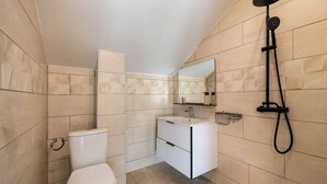 Un baño con inodoro, lavabo, espejo y ducha.