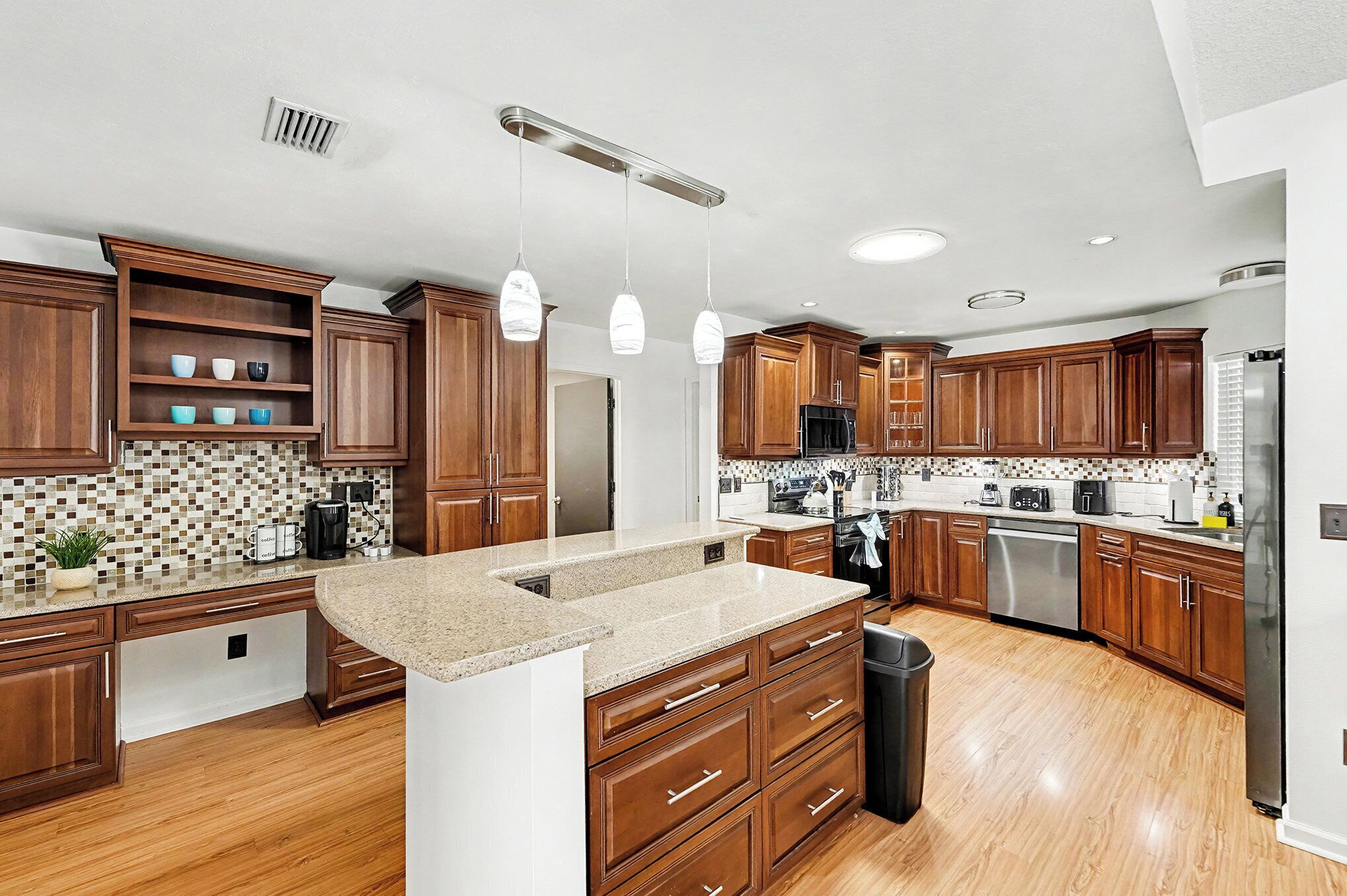 A modern kitchen with wooden cabinets, granite countertops, and stainless steel appliances.