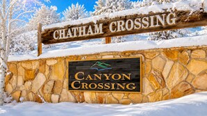 Un muro de piedra con un letrero de madera que dice 'CHATHAM CROSSING' y un logo encima.