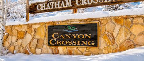 Un muro de piedra con un letrero de madera que dice 'CHATHAM CROSSING' y un logo encima.