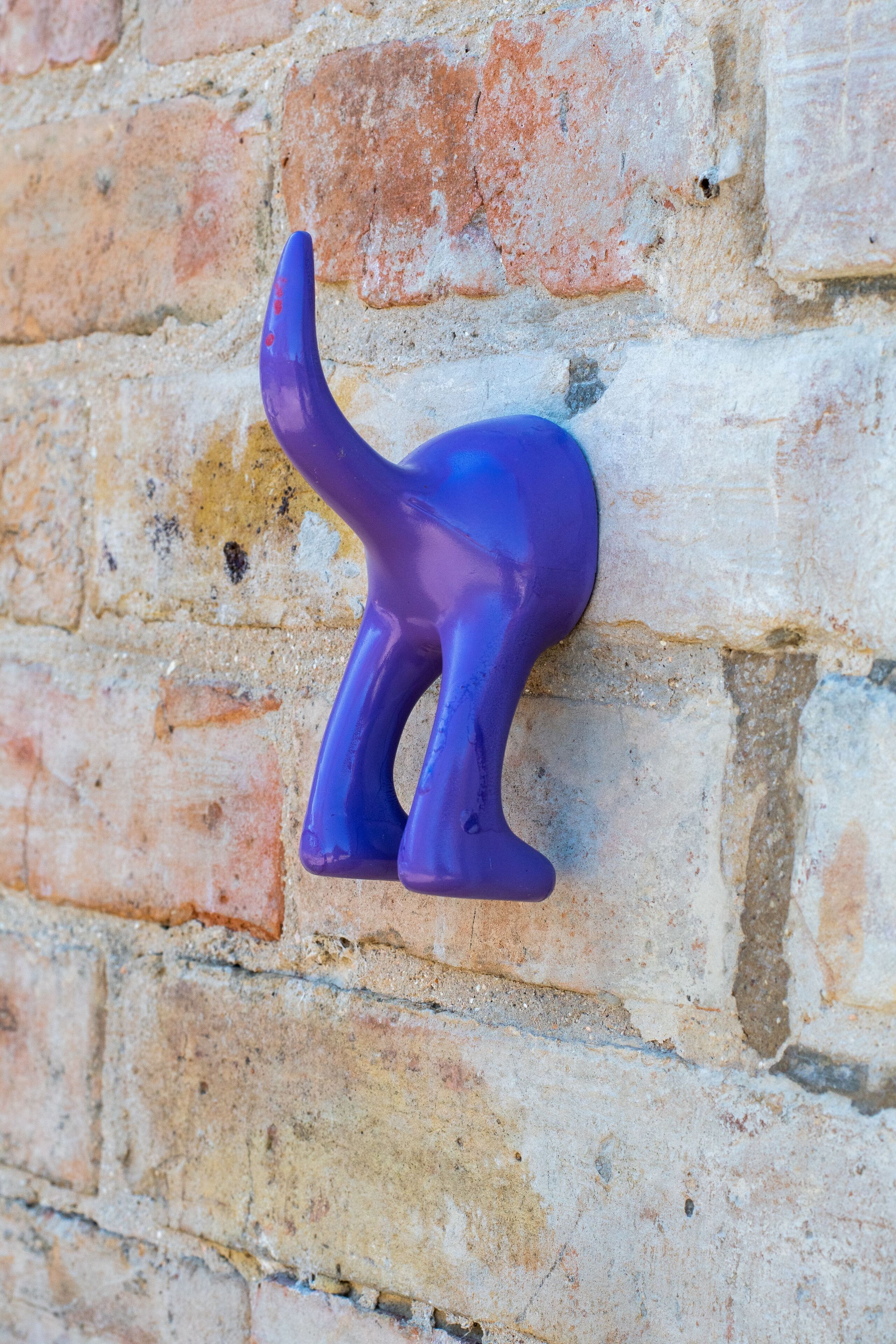 En lila dinosaurieskulptur som är monterad på en tegelvägg.