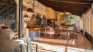 A rustic kitchen with a stone wall, wooden beams, and a tiled floor. - Verd Salvatge by Rentallorca (Muro)