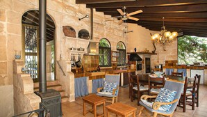 A rustic stone interior with a fireplace, wooden furniture, and a kitchen area. - Verd Salvatge by Rentallorca (Muro)