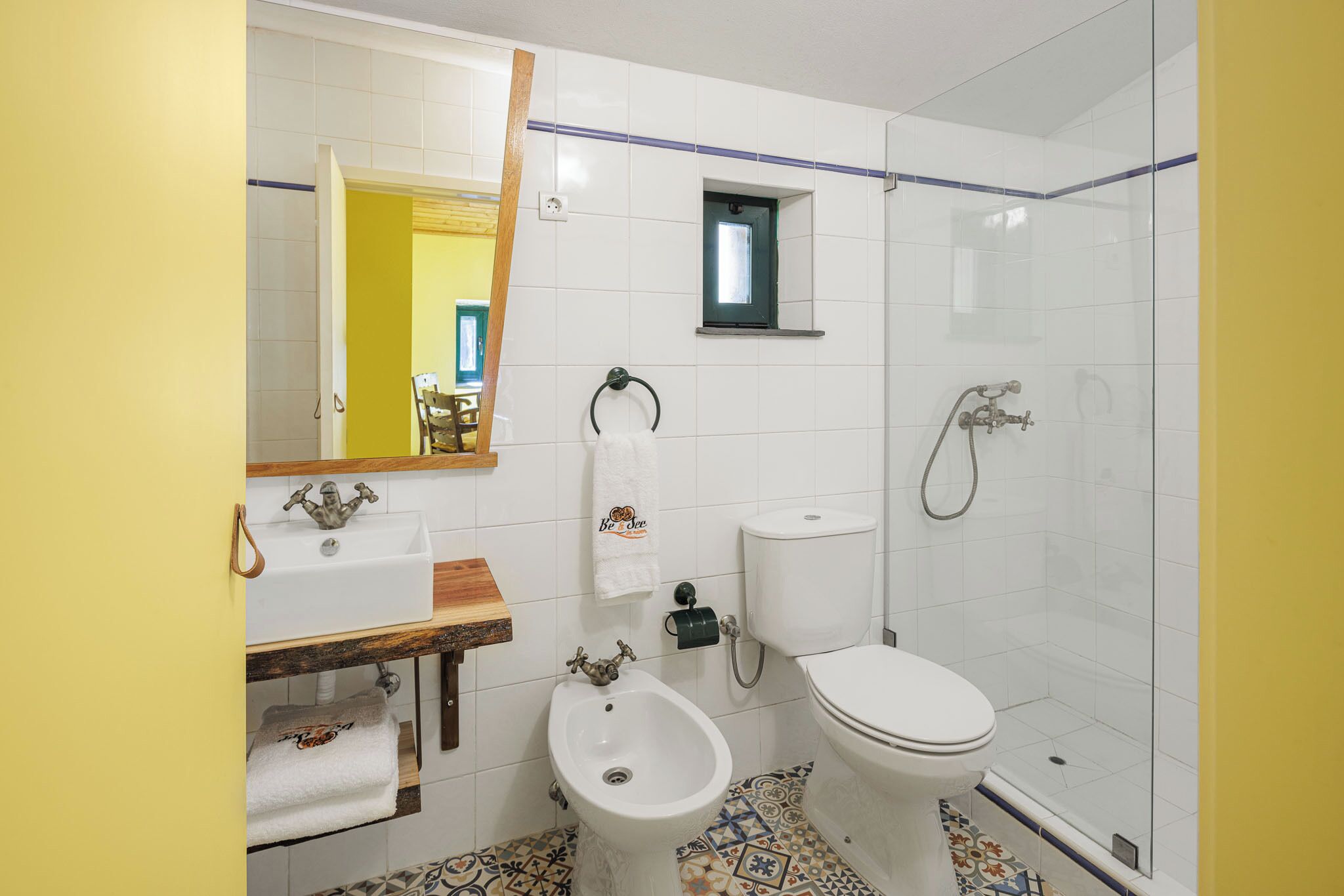 Un baño con lavamanos blanco, bidé, inodoro y cabina de ducha de vidrio.