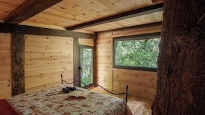 A wooden cabin room with a bed, a window, and a tree trunk. - Be&See In River (Ovar)
