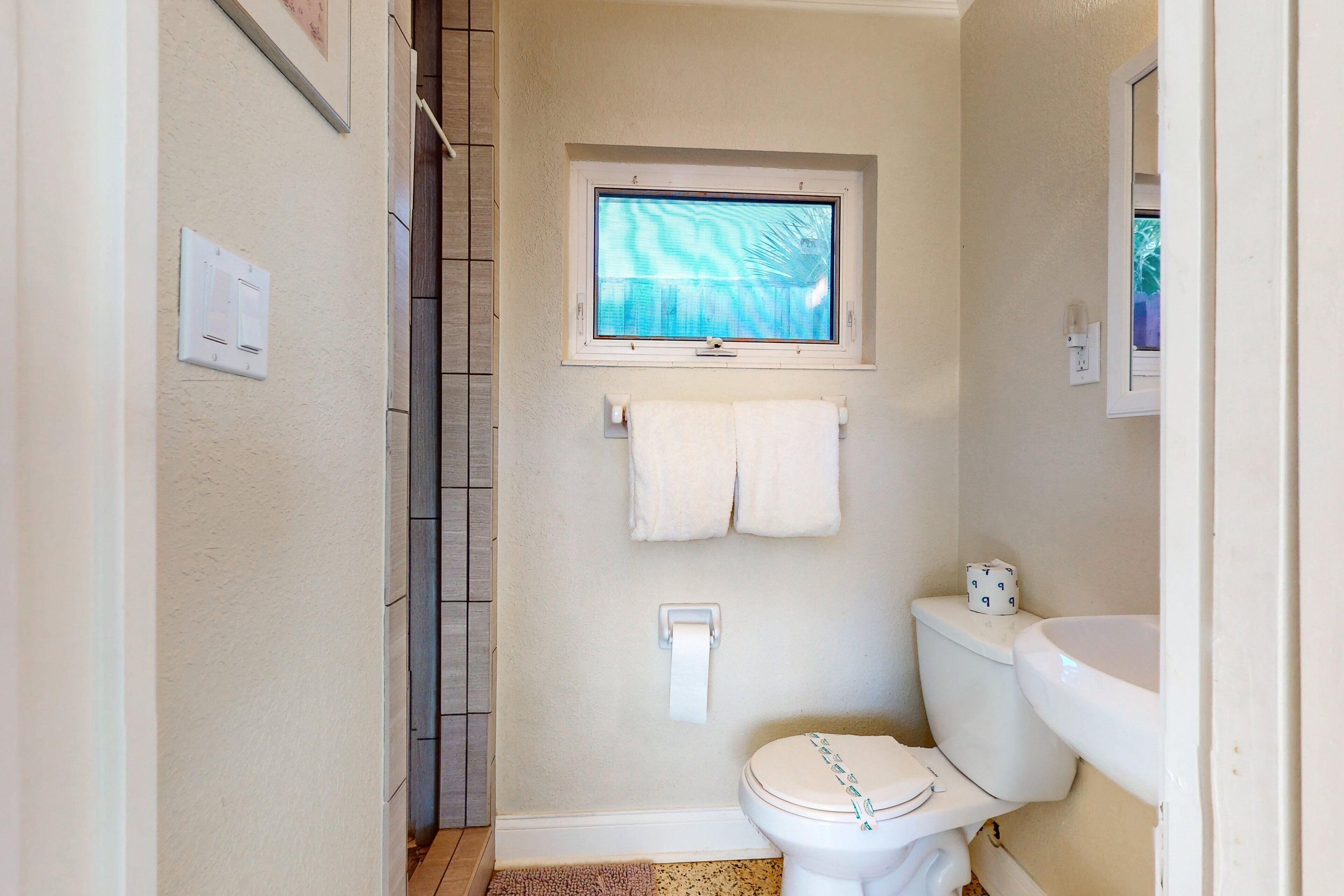 A small bathroom with a toilet, sink, and window.