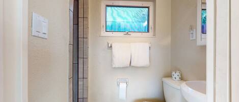 A small bathroom with a toilet, sink, and window.
