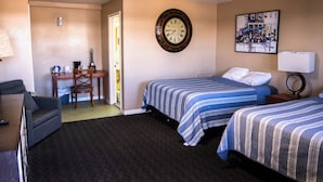 Ein Hotelzimmer mit zwei Betten, einem Schreibtisch mit Stuhl, einer Lampe und einer Wanduhr.