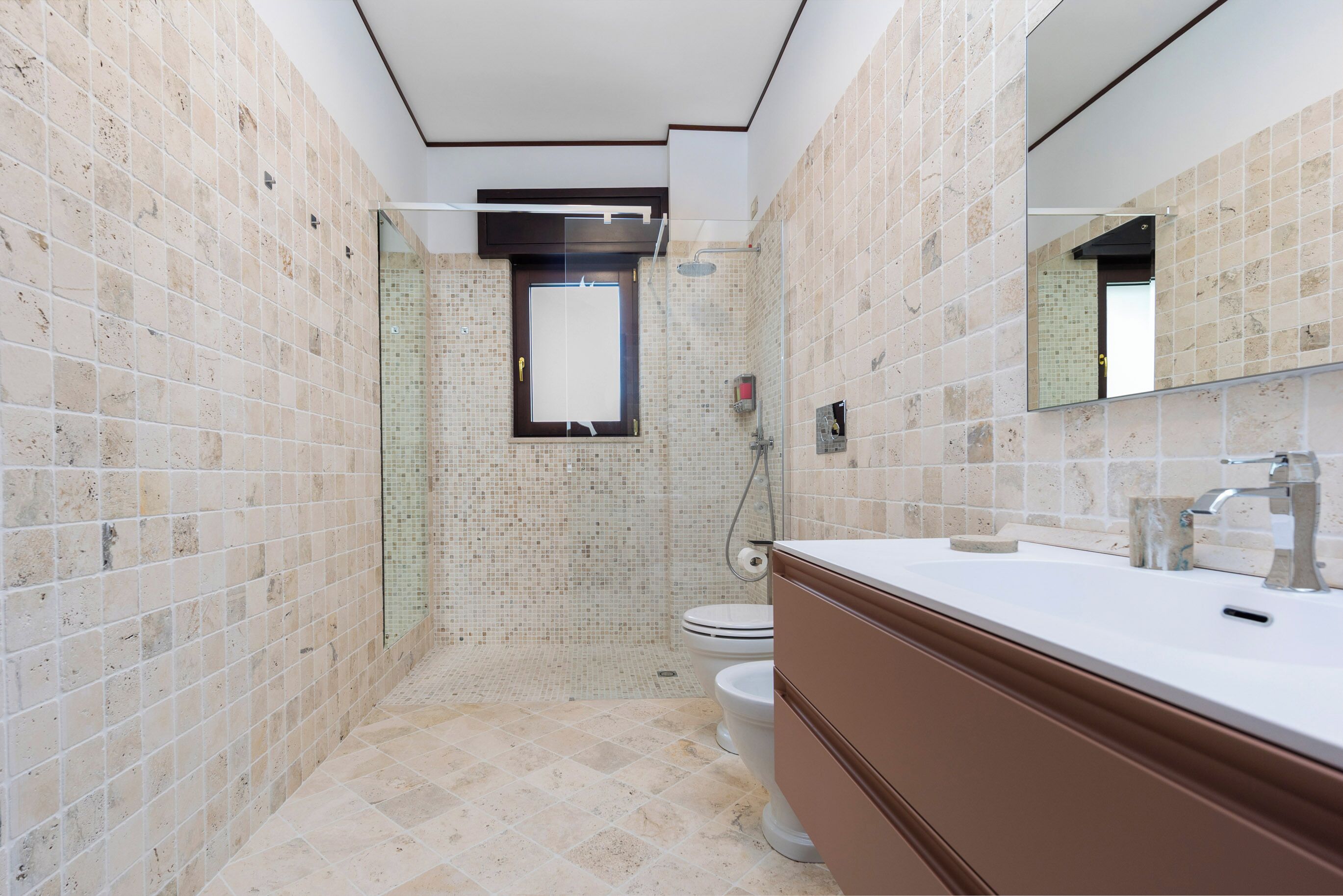 A bathroom with a shower, toilet, and a large mirror.
