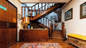 A wooden staircase with a railing, a patterned rug, and a bench with a cushion. - Reggio Suite Luxury B&B (Reggio Calabria)