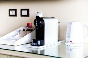 Máquina de café e chaleira em uma mesa de vidro.