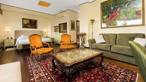 A hotel room with a bed, two armchairs, a sofa, a coffee table, and a large painting on the wall. - Reggio Suite Luxury B&B (Reggio Calabria)