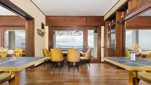 A conference room with a view of the mountains through large windows, wooden paneling, and yellow chairs. - Reggio Suite Luxury B&B (Reggio Calabria)