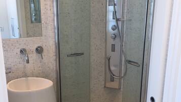 A modern bathroom with a glass-enclosed shower, a large white sink, and a mirror.