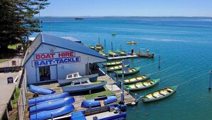 A boat hire bait tackle building with several boats docked at the pier. - View Street Lake House (The Entrance)