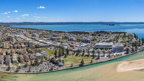 An aerial view of a coastal town with a marina, residential buildings, and a bridge connecting to the mainland. - View Street Lake House (The Entrance)