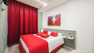 A modern bedroom with a large bed, red curtains, a nightstand, and a wall-mounted painting.