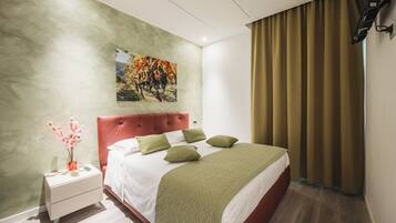 A modern hotel room with a large bed, a nightstand, a painting on the wall, and a window with curtains.