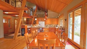 Une cuisine spacieuse avec des meubles en bois, une table à manger et des chaises. Un escalier mène à un niveau supérieur.