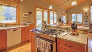 Une cuisine dotée de meubles en bois, d’une cuisinière et de grandes fenêtres donnant sur l’extérieur.
