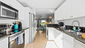 Een moderne keuken met witte kastjes, roestvrijstalen apparatuur en een zwart aanrecht.