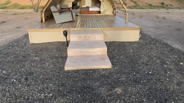 A triangular tent with a wooden deck, a bed, and a ladder. - Adventurer Camp (Bidiya)
