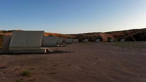 A desert landscape with multiple large tents arranged in a row. - Adventurer Camp (Bidiya)
