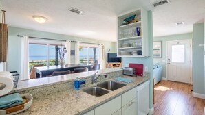A kitchen with granite countertops, a sink, and a dining area with a view. - Flagler Beach Escape in the Sun (Flagler Beach)