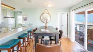 A dining area with a table, chairs, a large mirror, and a view of the ocean through a sliding glass door. - Flagler Beach Escape in the Sun (Flagler Beach)