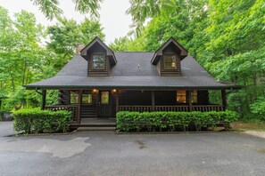 A log cabin with a porch, two dormer windows, and a chimney. - 1 mile to Parkway*PRIVATE*Sleeps 12*HotTub*FirePit (Pigeon Forge)