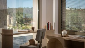 Um espaço de escrit ório moderno com uma mesa, cadeira e grandes janelas com vista para um jardim.