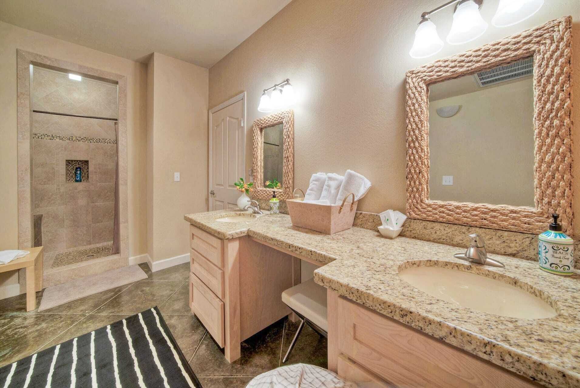 A bathroom with two sinks, a shower, and a large mirror with rope frames.