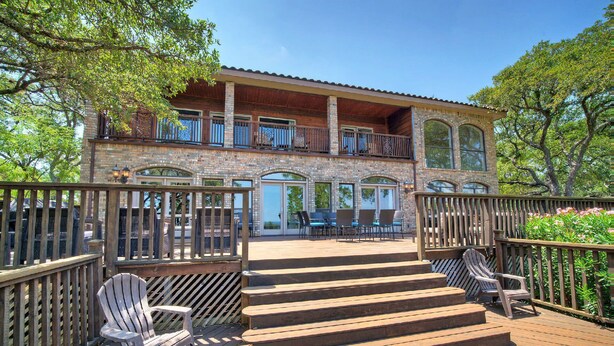 Un edificio a due piani con una veranda in legno, posti a sedere all'aperto e una facciata in mattoni.