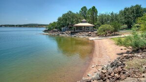 Un gazebo affacciato su un lago, con vista libera sull'acqua e gli alberi circostanti.