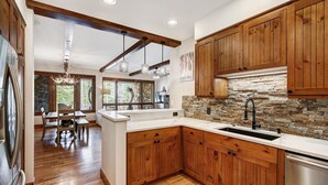Una cucina con mobili in legno, zoccolo in pietra e lavastoviglie integrata.
