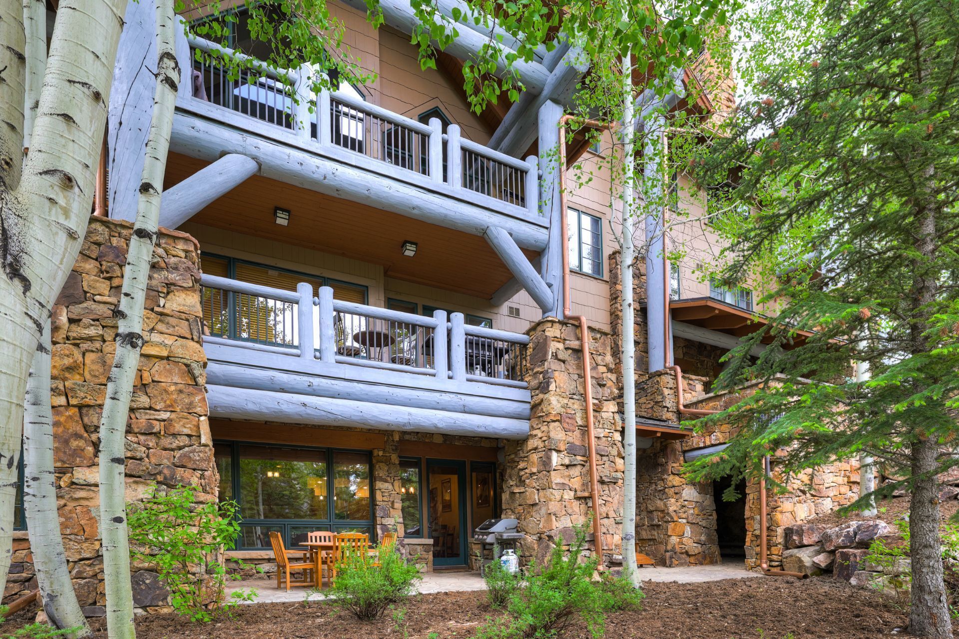 A multi-story lodge with stone and wood construction, featuring balconies and a covered outdoor seating area.