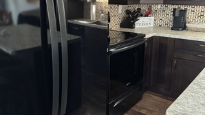 A modern kitchen with a stainless steel refrigerator, a microwave, and a coffee maker on the countertop.