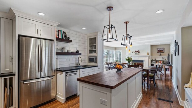 Una cocina moderna con un refrigerador de acero inoxidable, armarios blancos y una isla de madera.