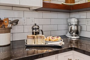A kitchen with white cabinets, a coffee maker, a stand mixer, and a tray with pastries. - Cozy Mid-Century Home Near Everything (Salt Lake City)