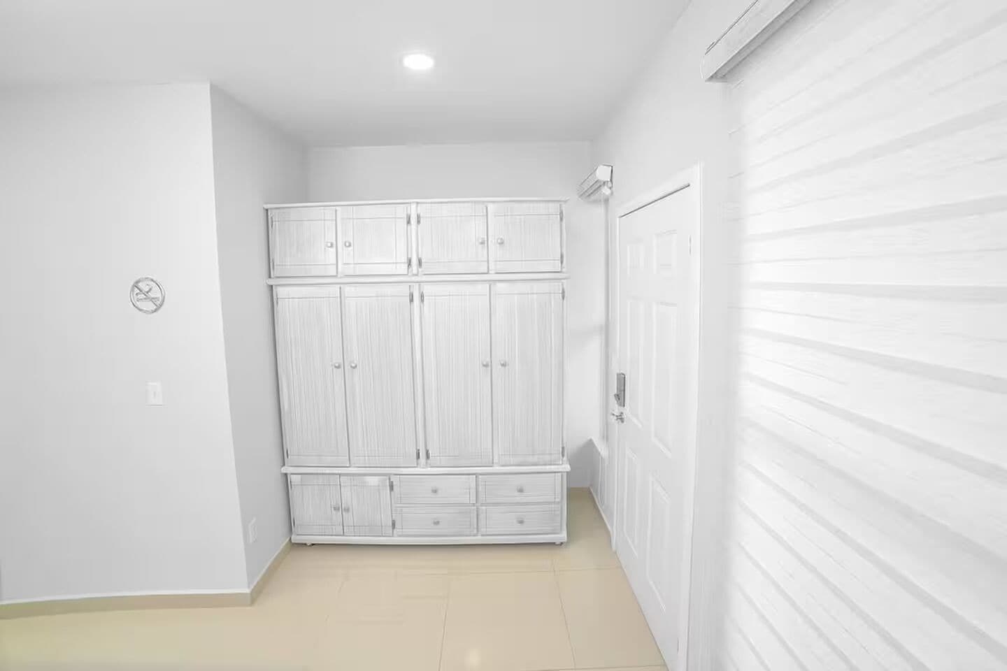 A room with a white wardrobe, a door, and a ceiling light.