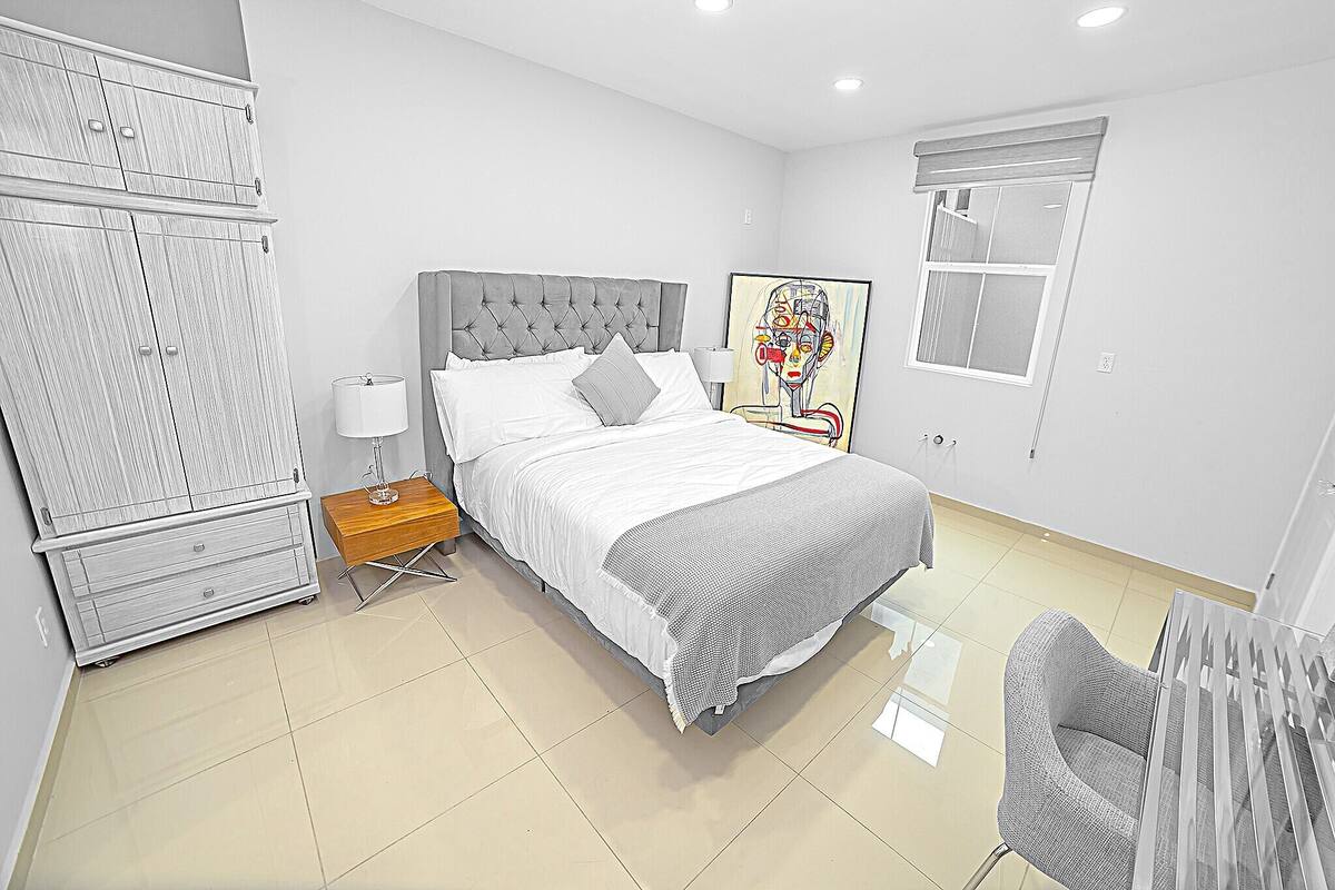 A modern bedroom with a bed, bedside table, lamp, and a large wardrobe.