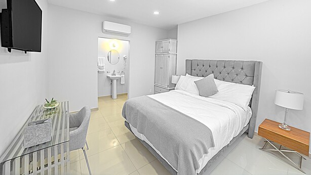 Une chambre à coucher moderne, comprenant un lit, une table de chevet, une chaise et un petit bureau avec une lampe.