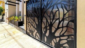 Une façade moderne, agrémentée d’un écran décoratif en métal et d’un jardinier avec des plantes.