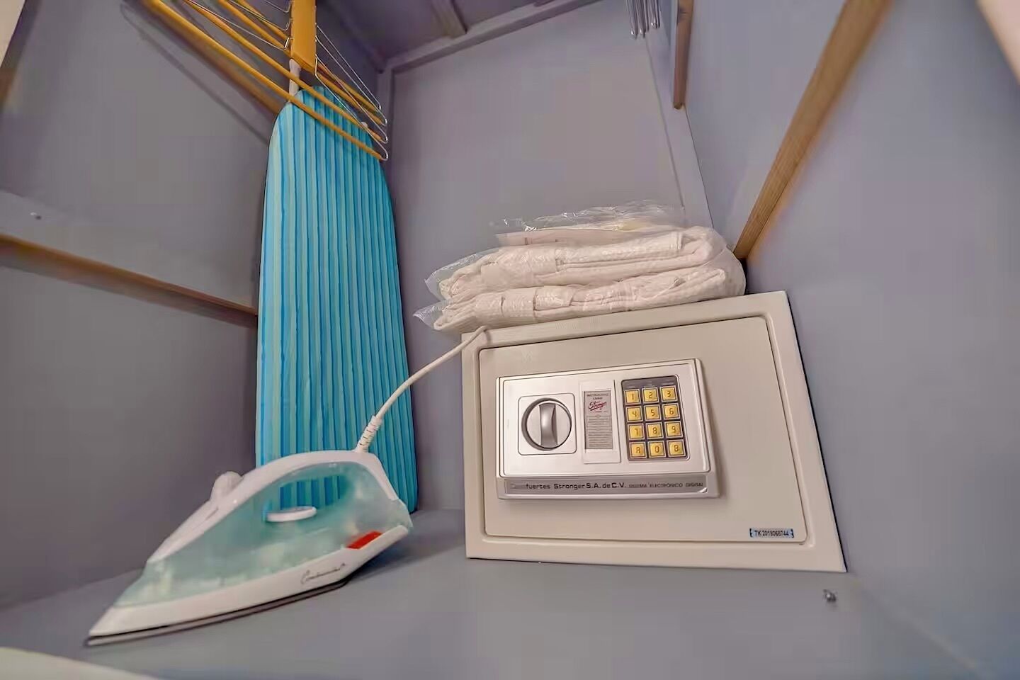 A compact room with a blue curtain, an iron, and a control panel.