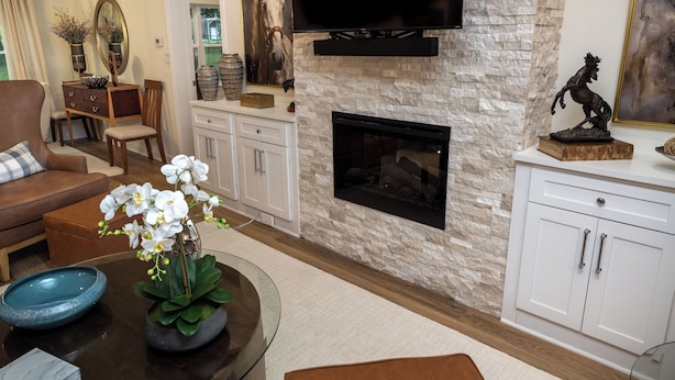 A living room with a stone fireplace, a television mounted above it, and a dining area with a wooden table and chairs. - Classy Country Guest House close to Canton First Monday (Wills Point)