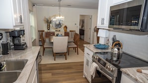 A modern kitchen with a built-in oven, a coffee maker, and a dining area with a chandelier. - Classy Country Guest House close to Canton First Monday (Wills Point)