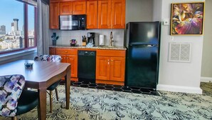 Una cocina compacta con una mesa y sillas, microondas, refrigerador y ventana con vista a la ciudad.