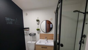 Une salle de bain moderne équipée de toilettes, d’un lavabo et d’une douche à parois en verre.