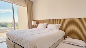 Een moderne hotelkamer met een groot bed, een plafondventilator en uitzicht op de omgeving.