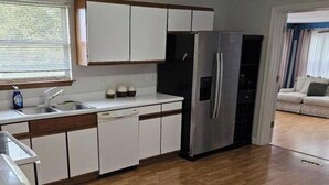 Una cocina moderna con armarios blancos, un refrigerador de acero inoxidable y una encimera de madera.